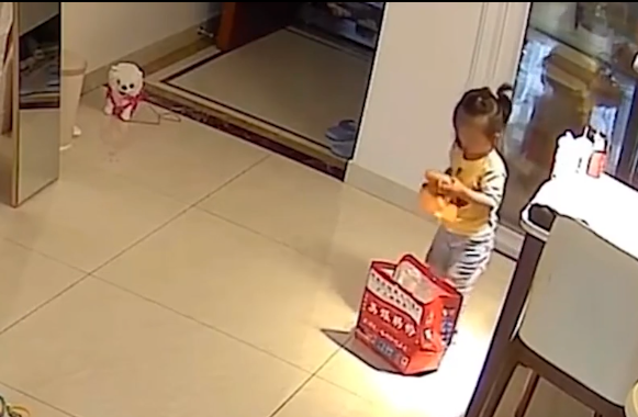 畫面可見女童踮起腳尖從飯桌上將保溫袋拿到地上,並打算幫媽媽將飯盒打包好。