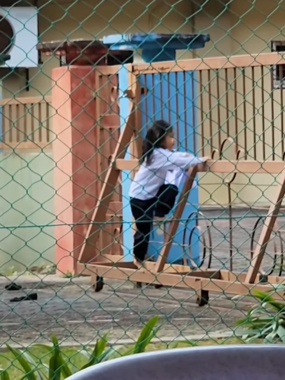 女童看準時機，趁沒有人在附近後，決定爬過校門的縫隙逃走。