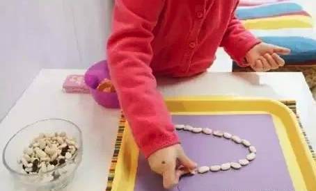 先把圖形畫在紙上，再讓孩子用豆子沿線擺放。