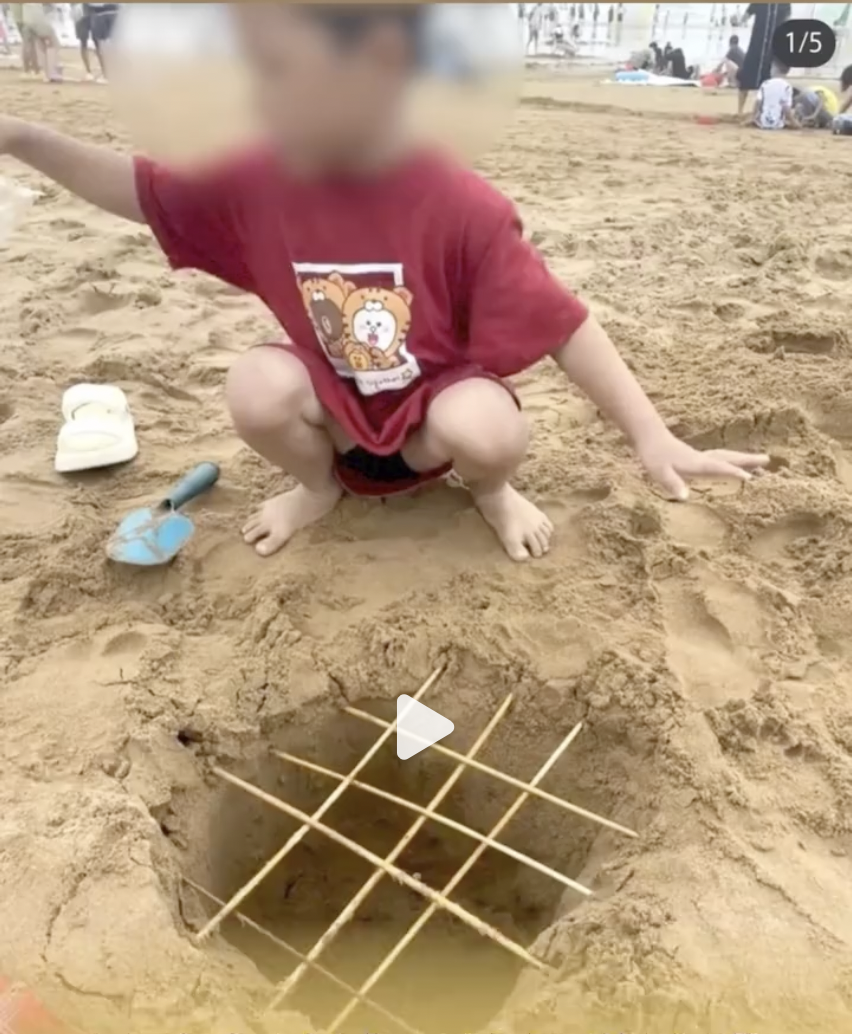 一名家長展示兒子在沙灘上製作的「陷阱」。