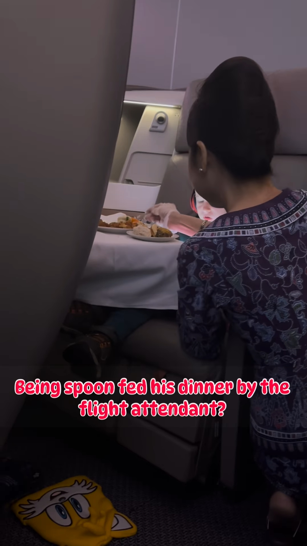 該名空姐戴上衛生手套，蹲在他兒子面前，用湯匙一口一口地給小朋友餵食。